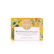 bar of soap wrapped in yellow paper printed with oranges and pears. There is also a gold seal with a crown and a white box saying 'Buckingham Palace Pear and Orange Blossom Premium English Soap Handmade in London'