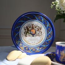 Blue round biscuit tin featuring the Royal coat of arms at the centre of the tin including the lion and the unicorn. Surrounding the coat of arms is a border of golden daffodils, roses, shamrocks and thistles. The tin is open to show the shortbreads insid