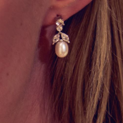 Pair of drop crystal earrings featuring a tear drop natural colour pearl supported by leave and circle shaped crystals. 