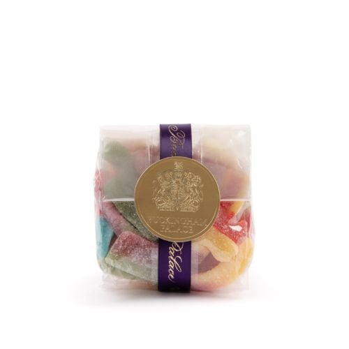 A transparent packet of sweets in multiple colours with purple Buckingham Palace ribbon and gold circular label