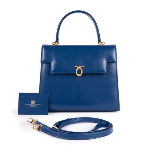 A dark blue leather handbag with top handle and gold coloured clasp