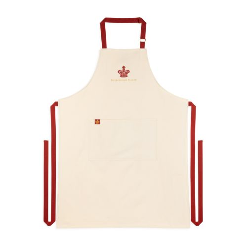 Cream coloured apron with deep red adjustable straps and large central pocket, red crown with Buckingham Palace spelled out in golden thread at the top centre. 
