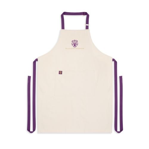 Cream coloured apron with deep purple adjustable straps and large central pocket, purple emblem featuring a stag with Palace of Holyroodhouse spelled out in golden thread at the top centre. 