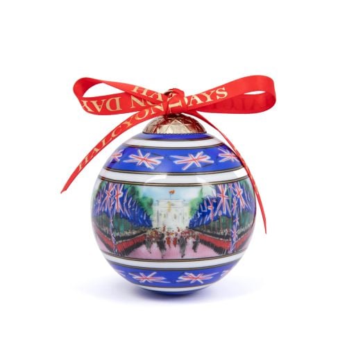 Halcyon Days blue china bauble with red ribbon and Trooping the Colour on the Mall painted on it. 