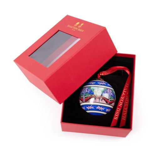 Halcyon Days blue china bauble with red ribbon and Trooping the Colour on the Mall painted on it. 