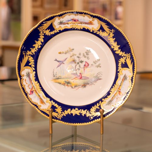 Image of the Prestige Sevres Cobalt Plate on stand, featuring three exotic birds at centre and cobalt blue edging with detailing. 