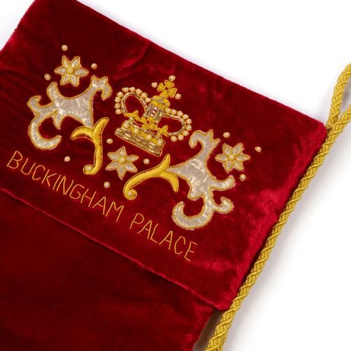 A red velvet stocking with a gold tassle and Buckingham Palace Emblem. 