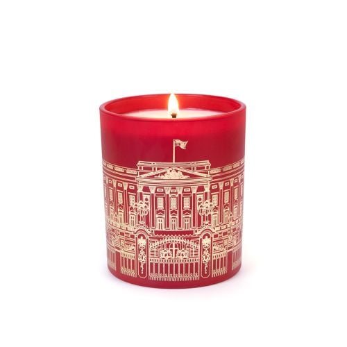 Lit red candle with Buckingham Palace Facade. 