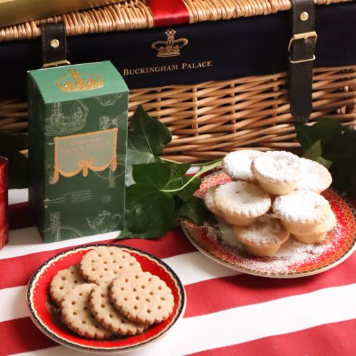 The 2024 Luxury Christmas Hamper, featuring a large wicker hamper on a red and white striped tablecloth, with a pack of mince pies, spiced marmalade, English Chocolate Truffles, festive spiced biscuits, spiced Christmas tea, and a tin of chocolate brazils