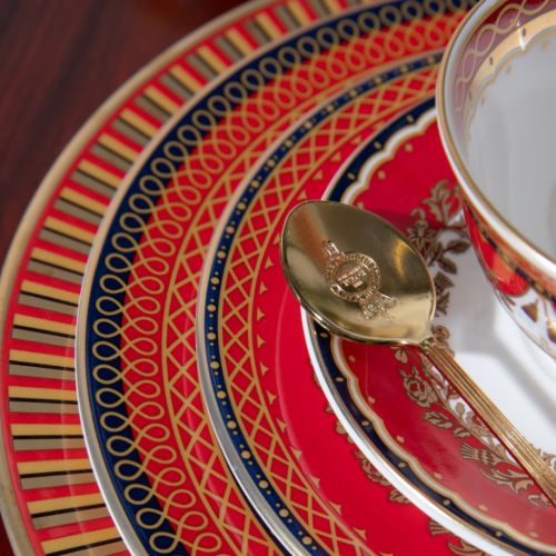 This Livery side plate features a deep, rich scarlet edge and navy border with contrasting fine gold details, inspired by the intricate decorative braiding of hand-sewn livery and regimental devices of ceremonial uniforms. The centre of the plate is white