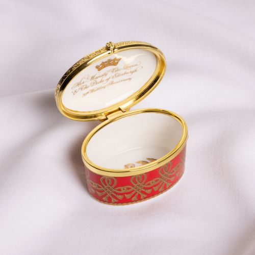 70th anniversary pill box with intricate gold and red design, featuring the entwined monogram of  The Queen and The Duke of Edinburgh featuring gold crown and tudor rose. 