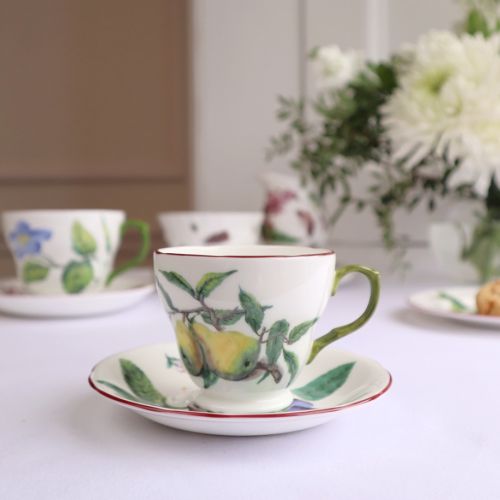 Chelsea porcelain teacup and saucer with box. White saucer with green handle. Both cup and saucer have red hand-painted rim. Decorated with berries, leaves and insects