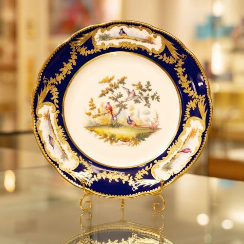 Image of the Prestige Sevres Cobalt Plate on stand, featuring three exotic birds at centre and cobalt blue edging with detailing. 