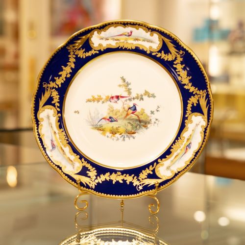 Image of the Prestige Sevres Cobalt Plate on stand, featuring three exotic birds at centre and cobalt blue edging with detailing. 