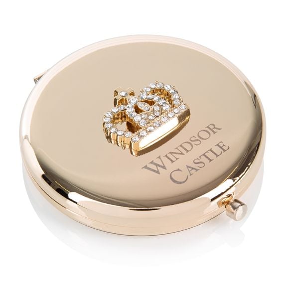 Round, gold compact mirror with Windsor Castle engraved on the top and a crown encrusted with clear crystals. 