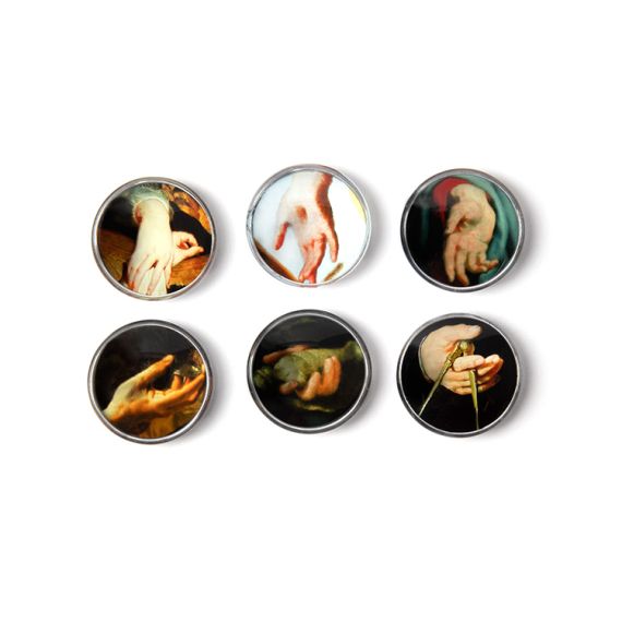 six circular glass magnets depicting paintings of hands