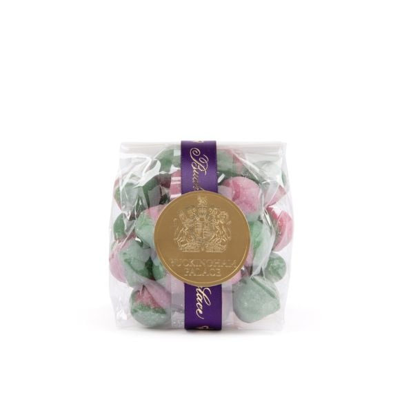 A transparent packet of Rosey Apple sweets in pink and green, tied with a purple Buckingham Palace ribbon and circular gold label