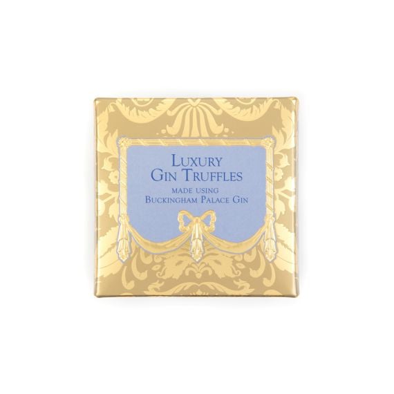 A golden chocolate box with blue writing and centre, stating "Luxury Gin Truffles, made using Buckingham Palace Gin."