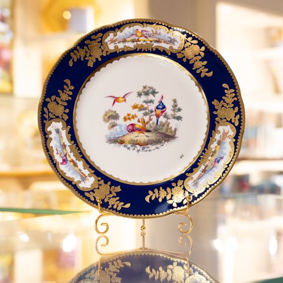 Image of the Prestige Sevres Cobalt Plate on stand, featuring three exotic birds at centre and cobalt blue edging with detailing. 