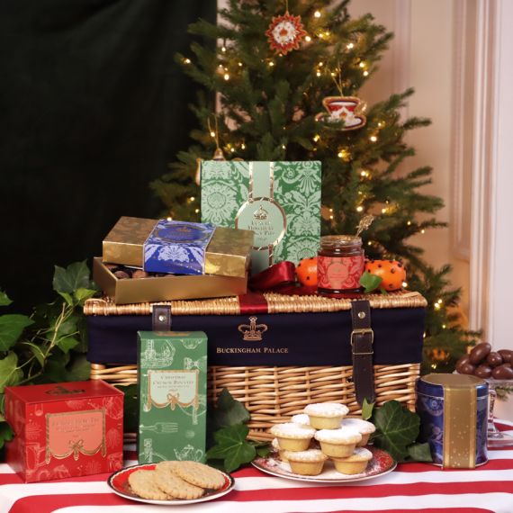 The 2024 Luxury Christmas Hamper, featuring a large wicker hamper on a red and white striped tablecloth, with a pack of mince pies, spiced marmalade, English Chocolate Truffles, festive spiced biscuits, spiced Christmas tea, and a tin of chocolate brazils